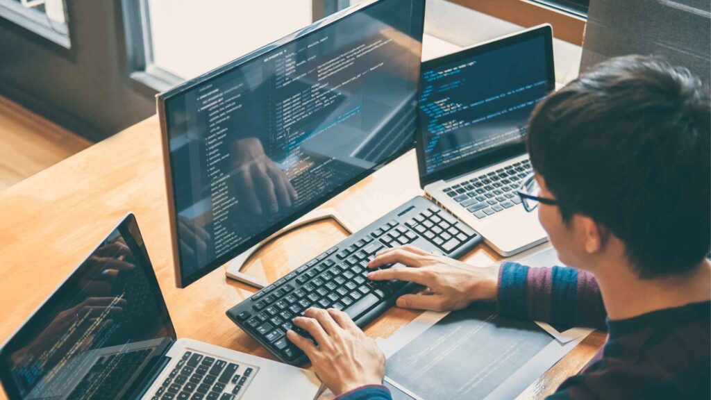 desenvolvedor de software programando em múltiplas telas e notebooks