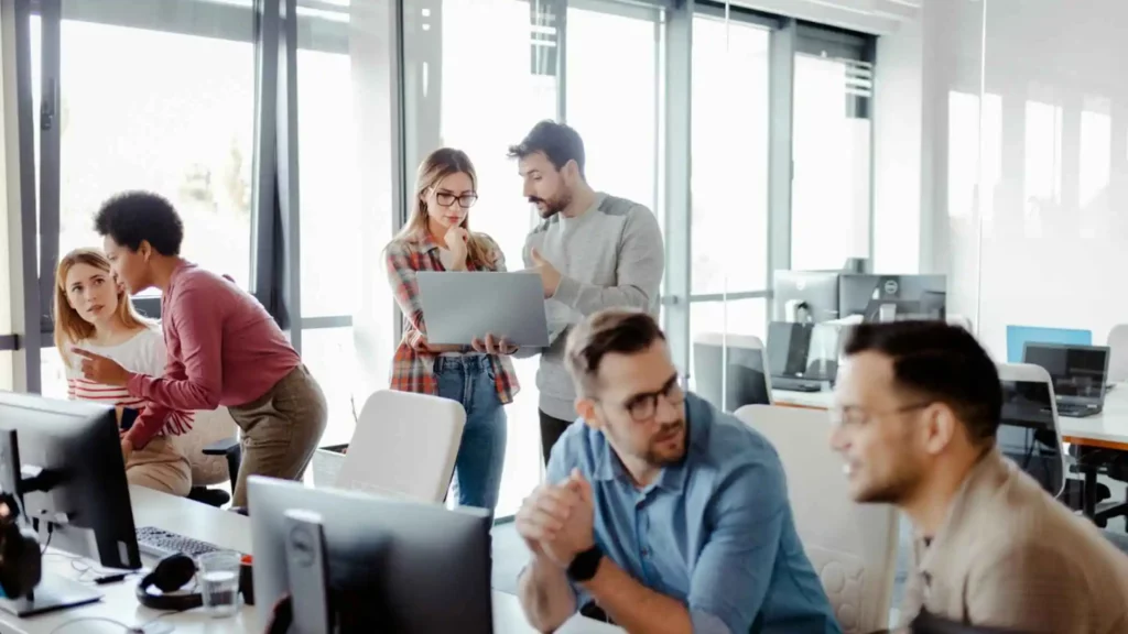 Equipe de profissionais de TI colaborando em um escritório moderno durante projeto de tecnologia
