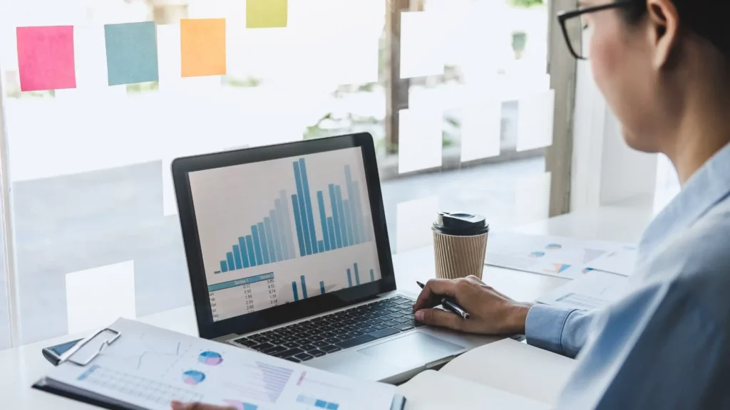 Profissional analisando gráficos de desempenho e indicadores em notebook com ferramentas para análise de dados
